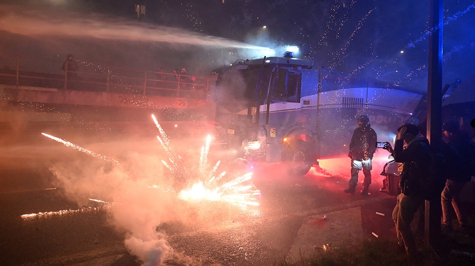 fireworks-fly-as-hooded-protesters-clash-with-police-after-olympics-open-in-milan